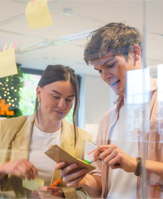 twee collega's maken notities en plakken post its in scrum werkwijze